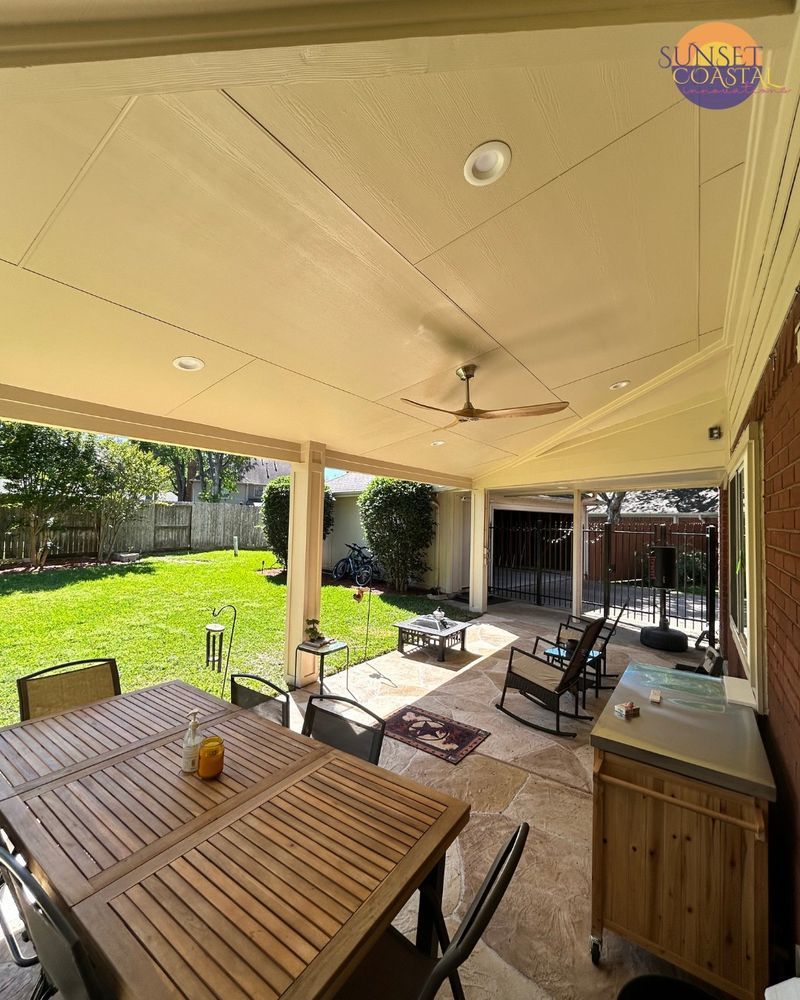 Covered patio with dining table, grill, and backyard view.
