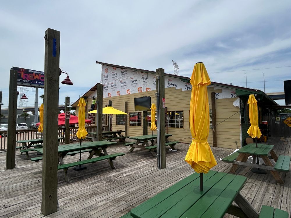 Outdoor restaurant patio with yellow umbrellas and green picnic tables.