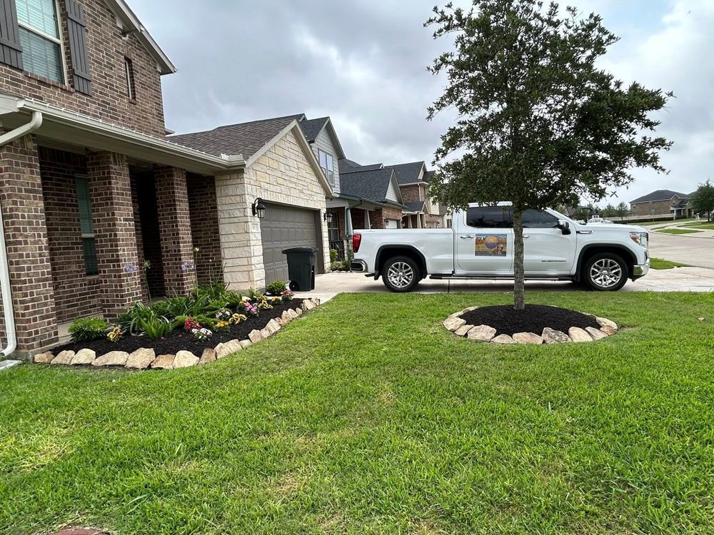 White truck parked by a home with flower beds and tree in front yard.