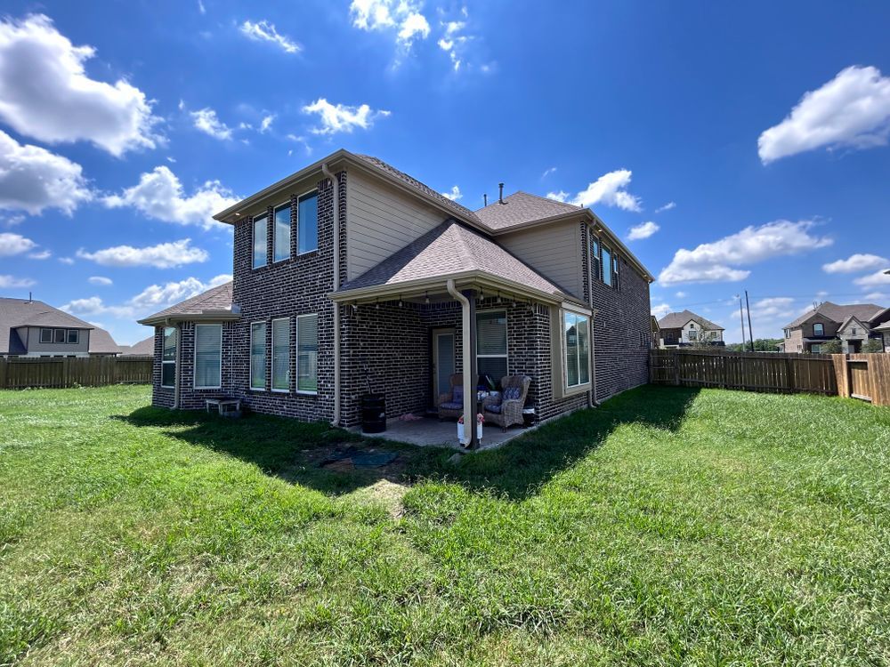 Back of a two-story brick house with a green lawn and blue sky.