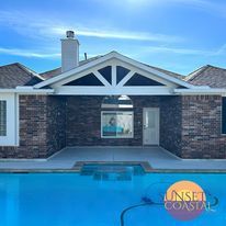 Pool with house in background; brick exterior, white trim, blue sky. 