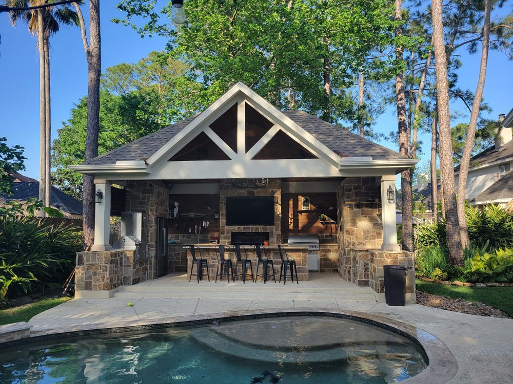 Outdoor kitchen with bar, pool, and stone accents.
