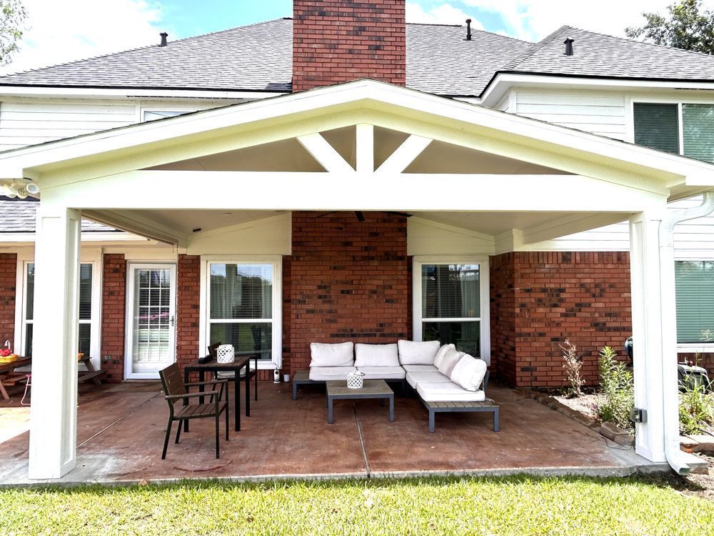 Covered patio with seating, brick wall, and a white roof structure.