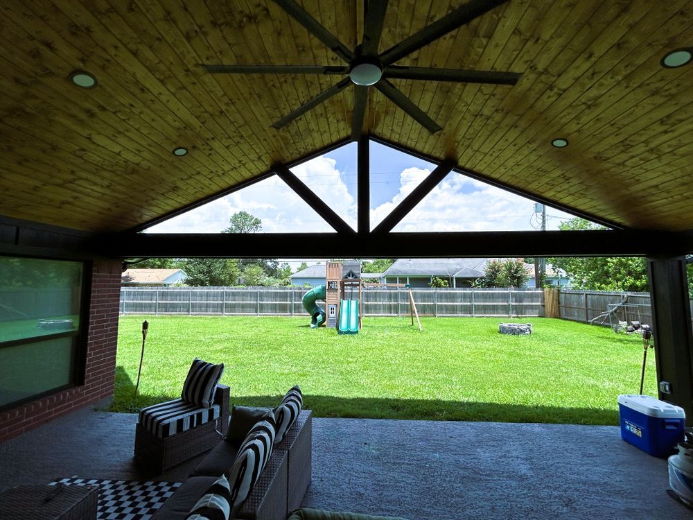 Outdoor covered patio with seating overlooking a backyard with a playset.