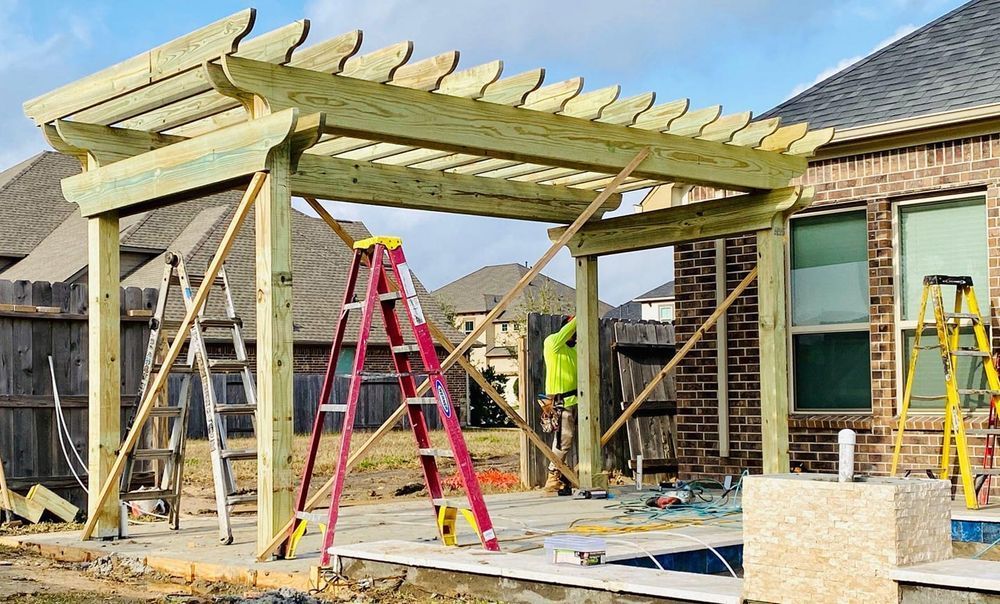 Pergola under construction on a patio, supported by bracing and ladders.