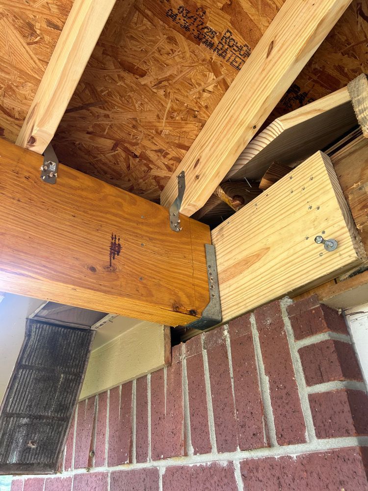 Wooden beam connected to brick wall with metal brackets. Interior view of building structure.