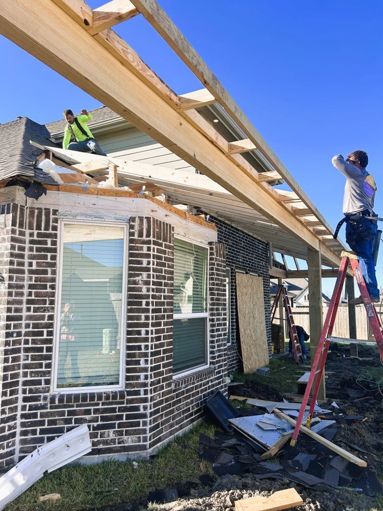 Construction workers building a covered patio on a brick house.