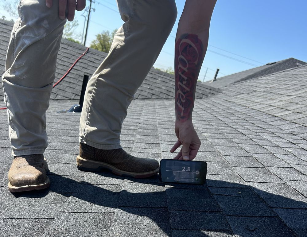 Person on a roof measures with a smartphone. Their arm has a 