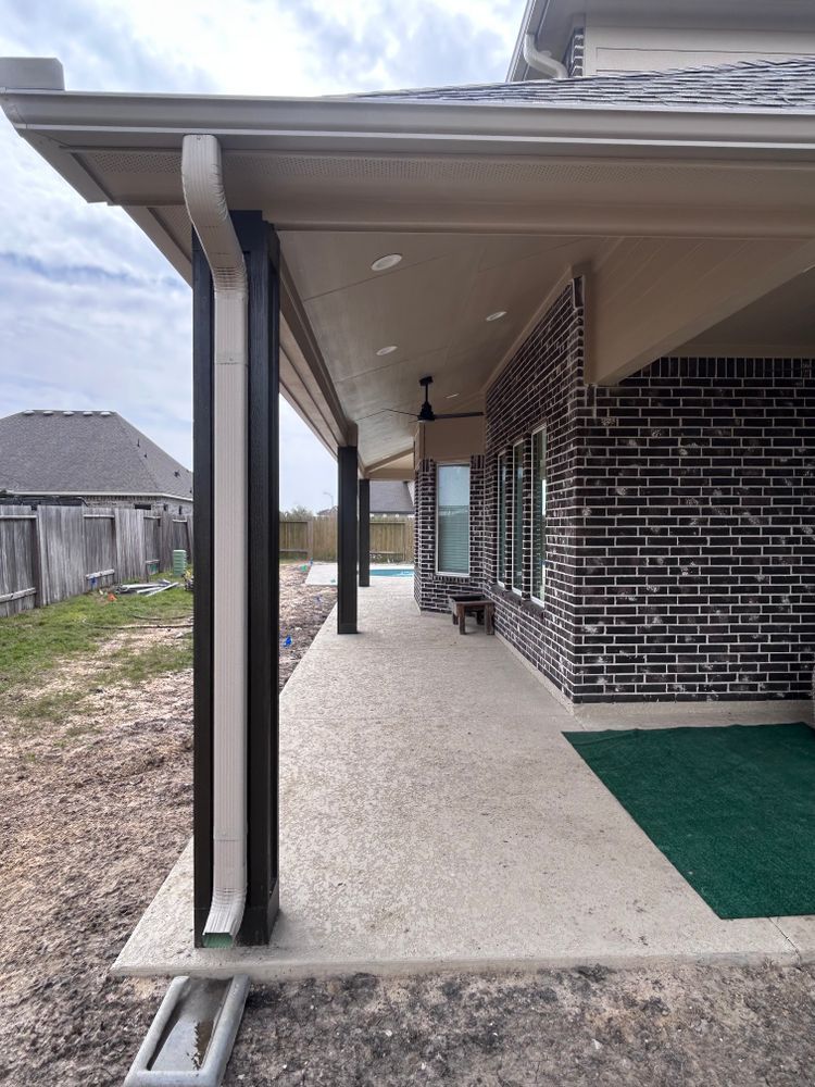 Covered patio with concrete floor, brick wall, and black support columns.