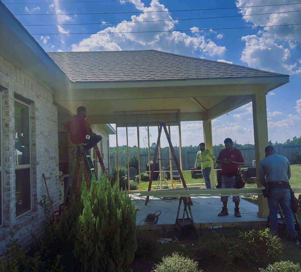 Construction workers building an outdoor structure, with framing in progress, on a sunny day.