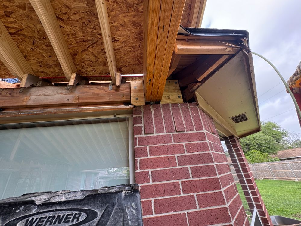 Brick column supports a wooden beam with plywood sheeting above. Construction site.