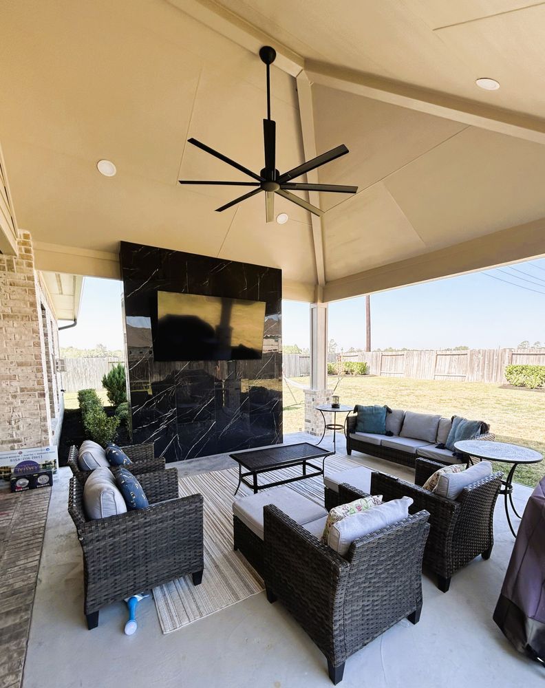 Outdoor patio with black fireplace, TV, seating, and ceiling fan.