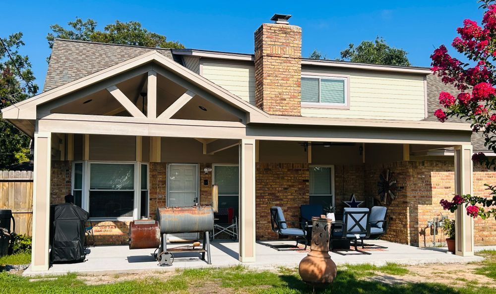 House with covered patio, brick and beige exterior, outdoor furniture, green grass, blue sky.