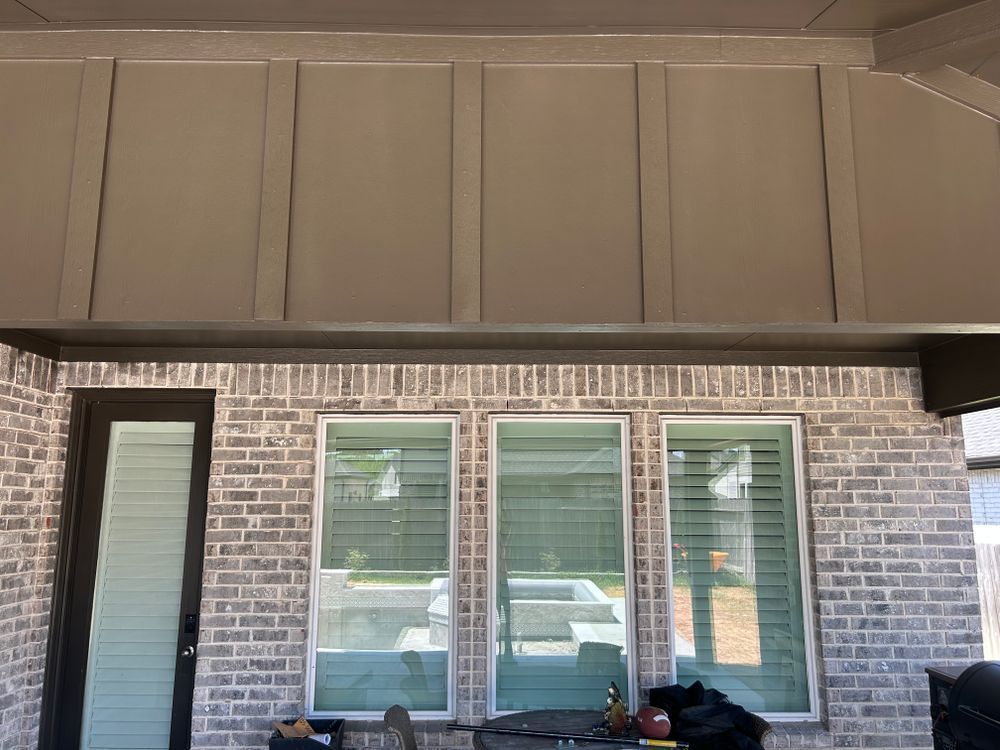 Gray brick patio with three windows and a dark door, under a gray panel ceiling.