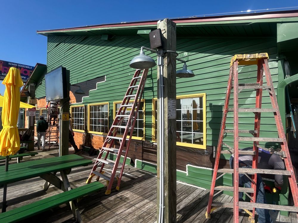 Two red ladders leaning against a green building. Outdoor setting with a yellow umbrella and wooden deck.