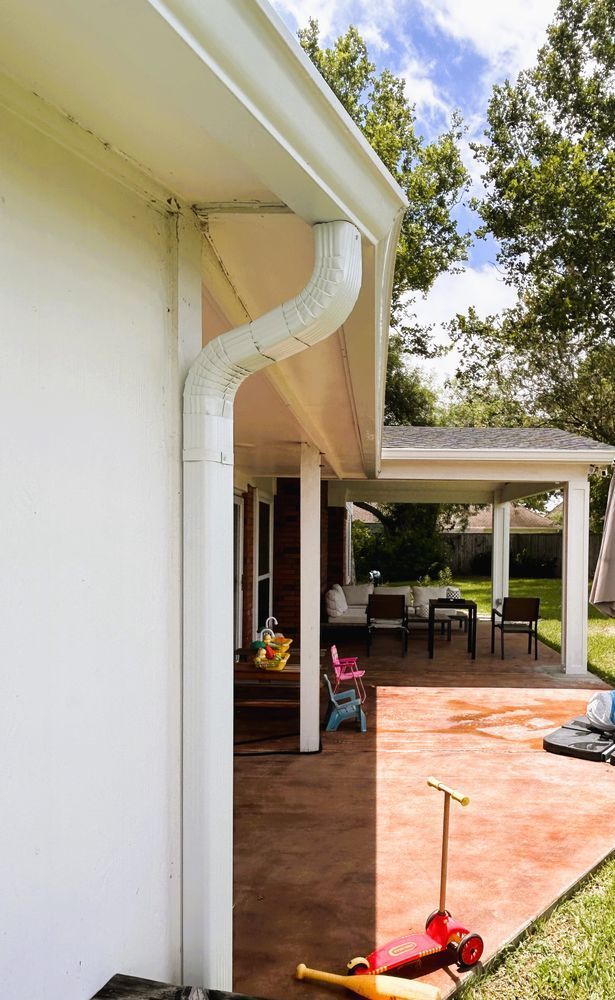 White house exterior with gutter and downspout, outdoor patio with seating.