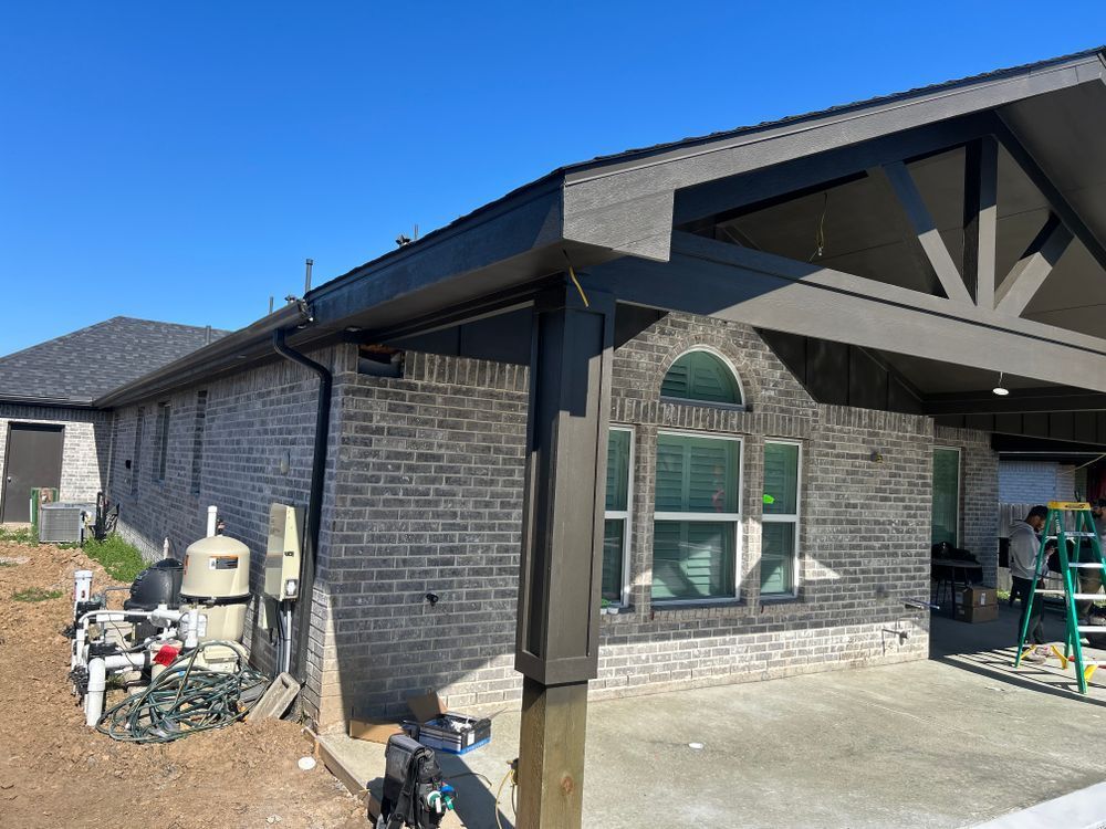 Gray brick house with a dark gray roof and trim. Construction is ongoing.