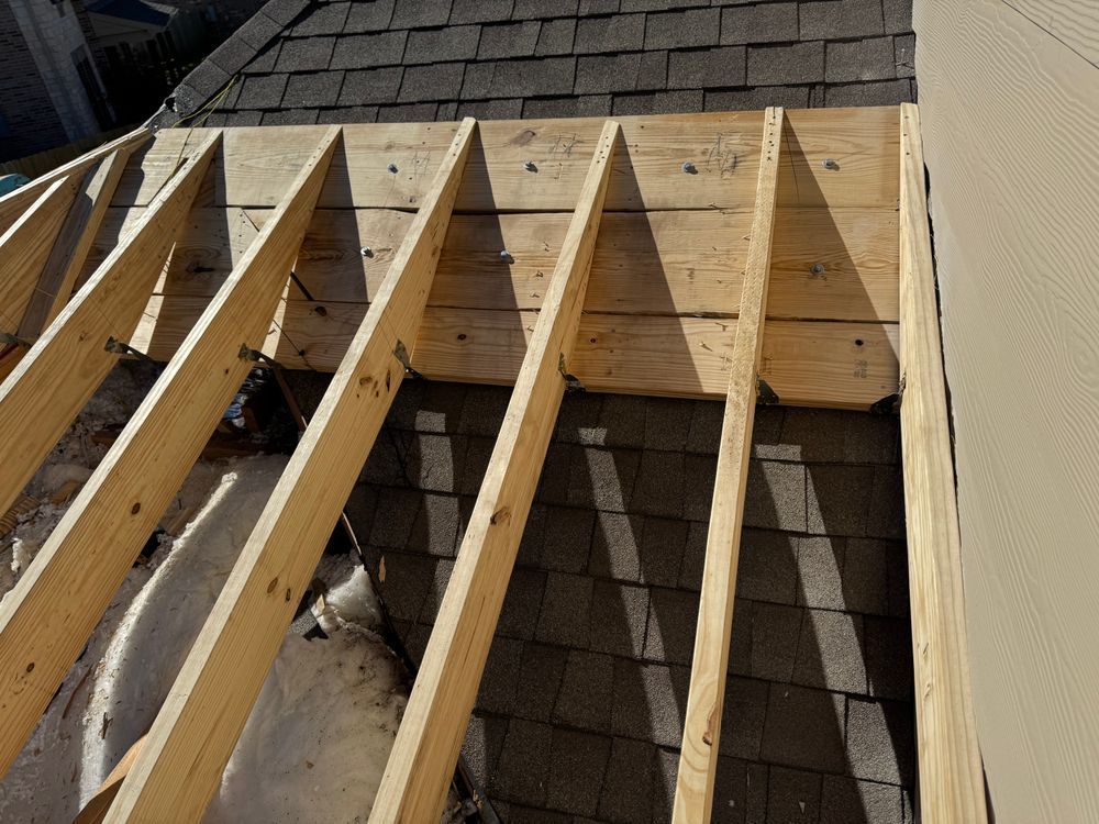 Wooden roof frame under construction on top of shingles.