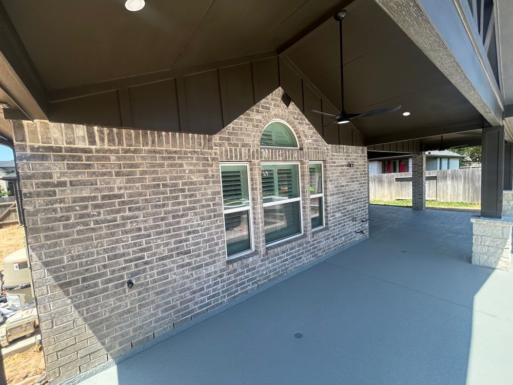 Brick wall with windows on a patio. Gray paint on the floor and ceiling, with columns.