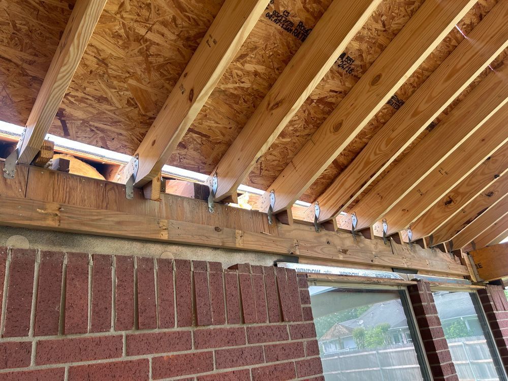 Wooden roof under construction attached to a brick wall.