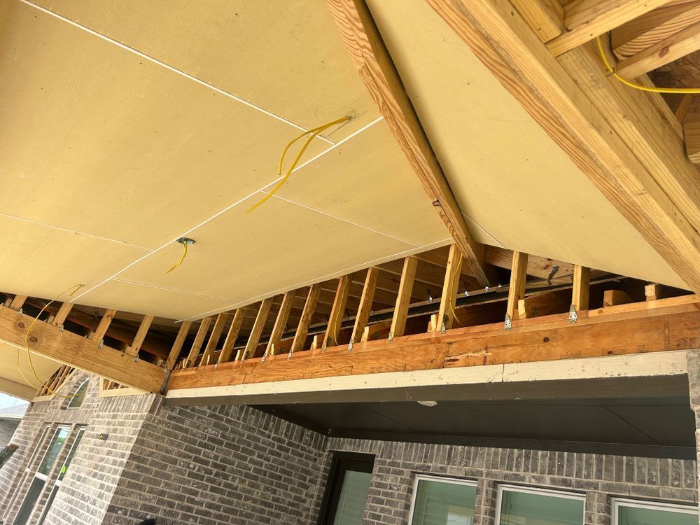 Construction of an outdoor patio ceiling with wood framing, drywall, and electrical wiring.