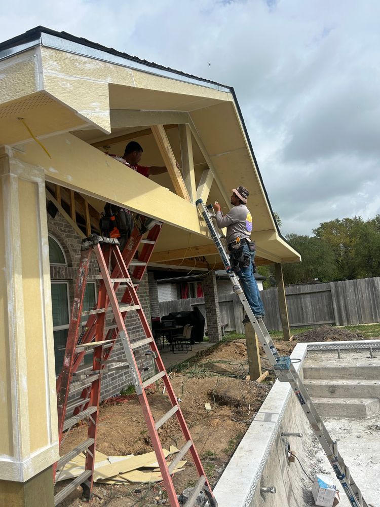 Two workers on ladders installing an awning over a house, a pool under construction.