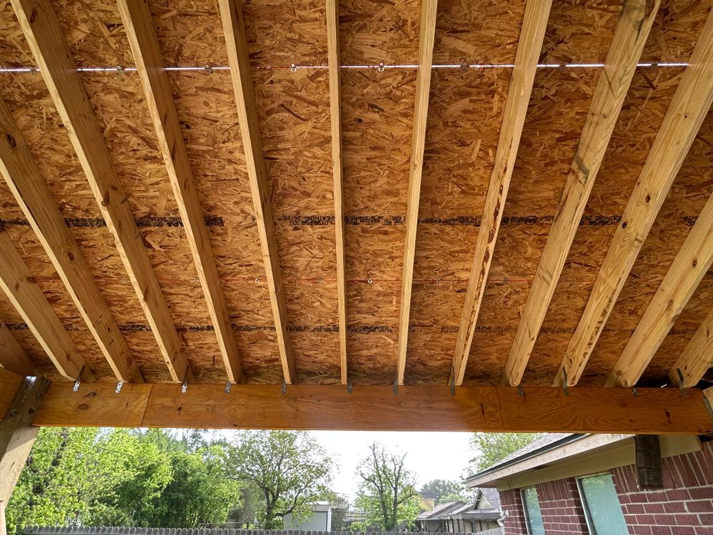 Wooden roof frame, with exposed beams and OSB sheathing, seen from below.