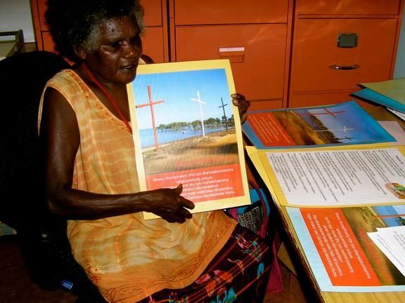 A woman is sitting at a desk holding a picture of a cross