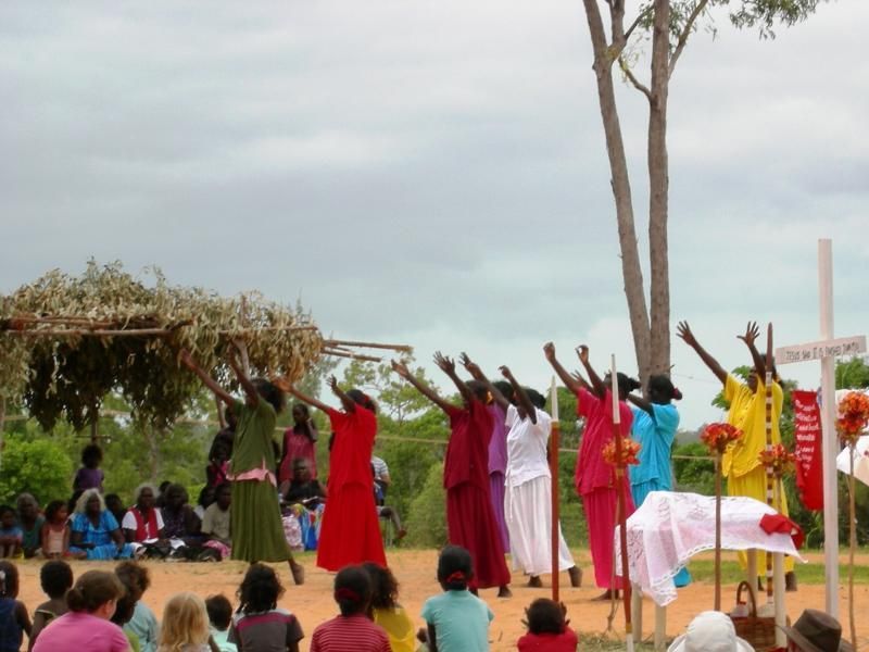 A group of people standing in front of a tree with their arms in the air