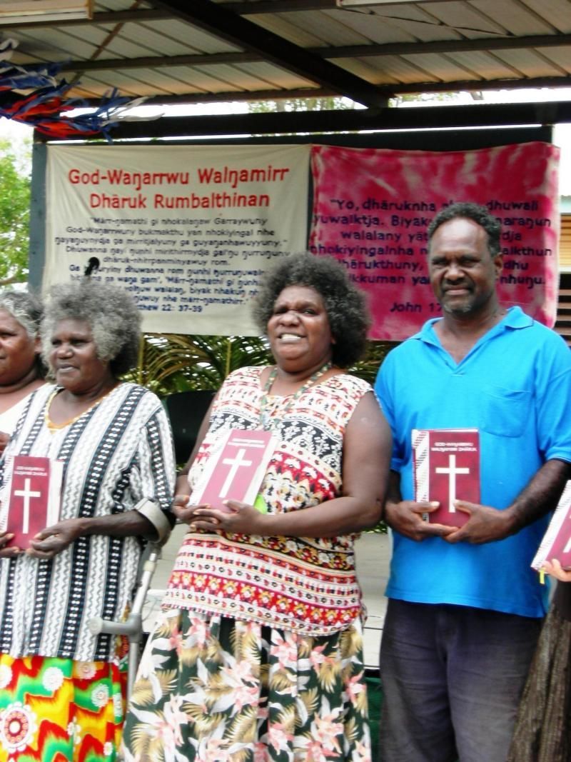 A group of people holding books with a cross on them