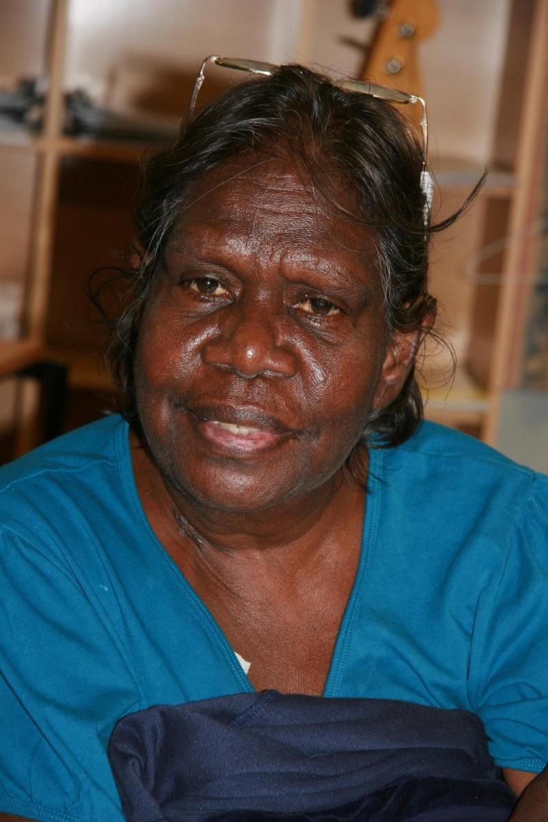 A woman wearing glasses and a blue shirt smiles for the camera