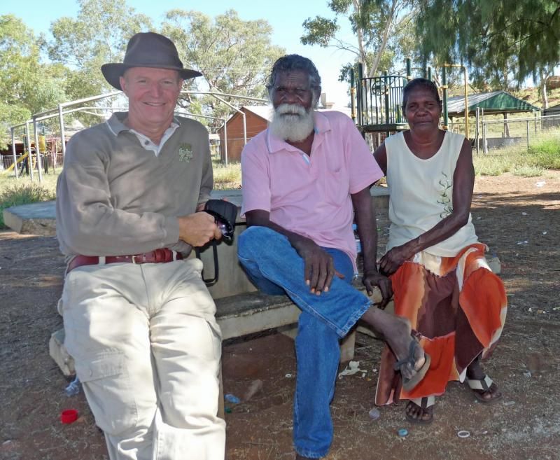 A man in a hat sits on a bench with two other people
