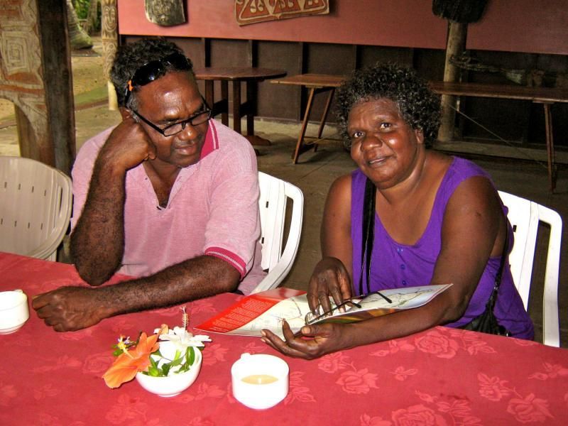 A man and a woman are sitting at a table looking at a menu
