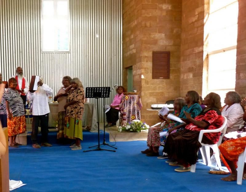 A group of people are sitting in a room with a blue carpet
