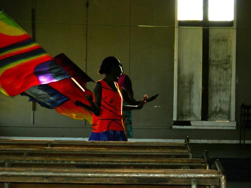 A woman in a red top is holding a rainbow flag