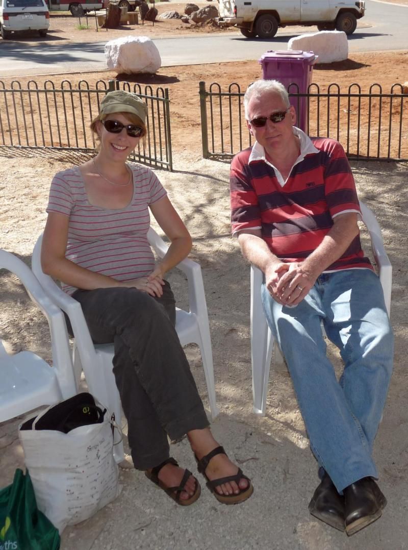 A man and a woman are sitting in chairs in the sand