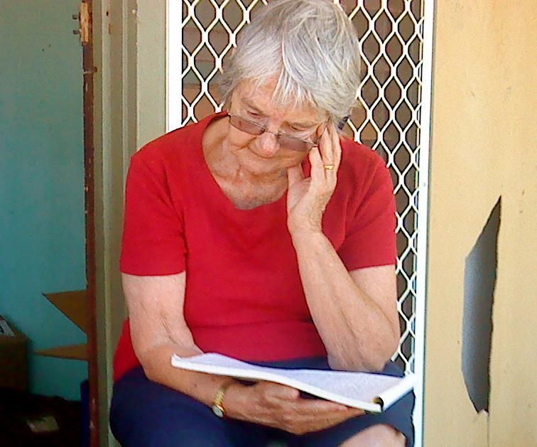 A woman in a red shirt is reading a book