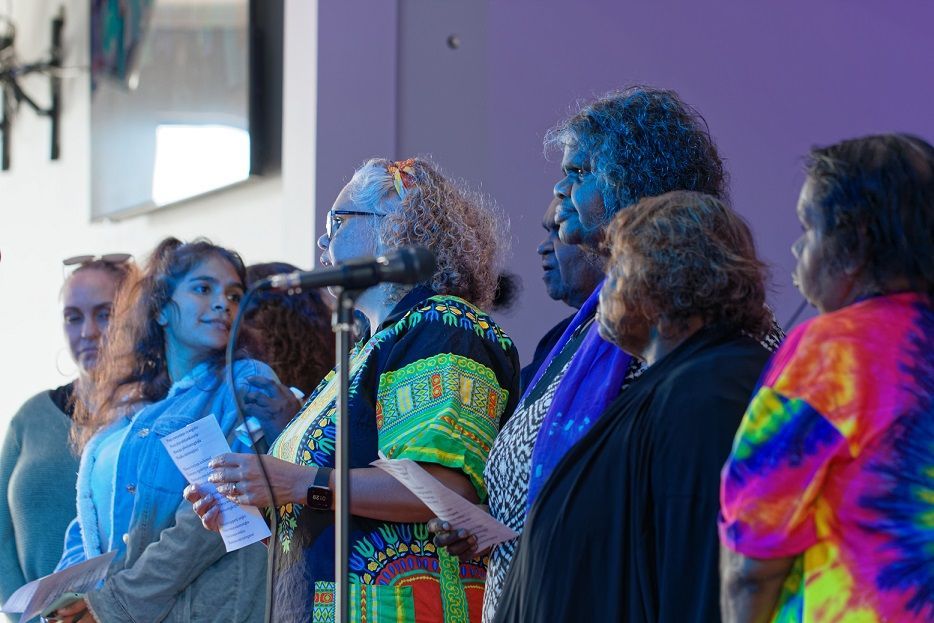 A group of women are standing in front of a microphone.