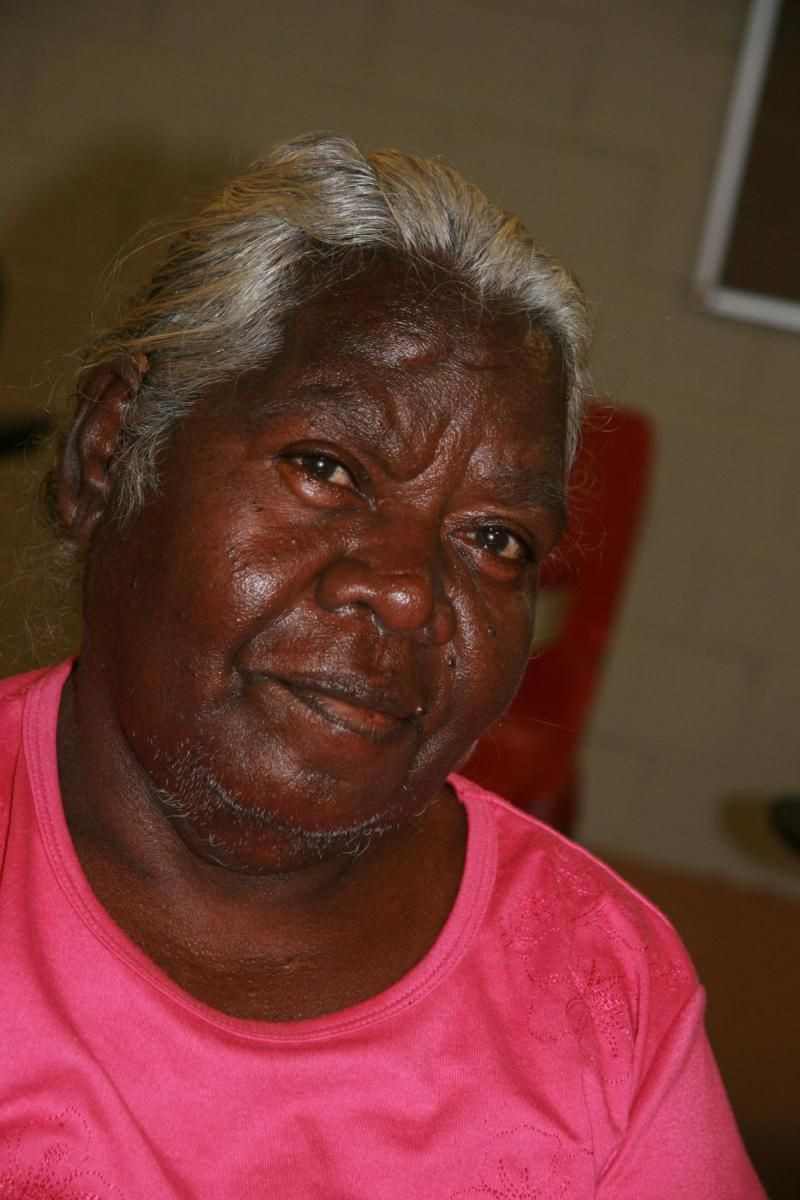 A close up of a woman 's face wearing a pink shirt.