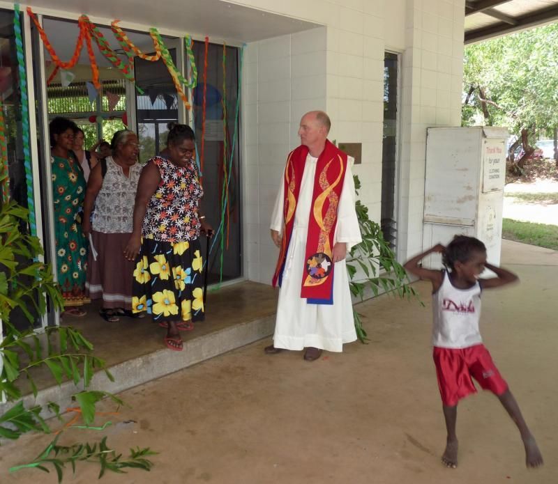 A man in a white robe stands in front of a group of people