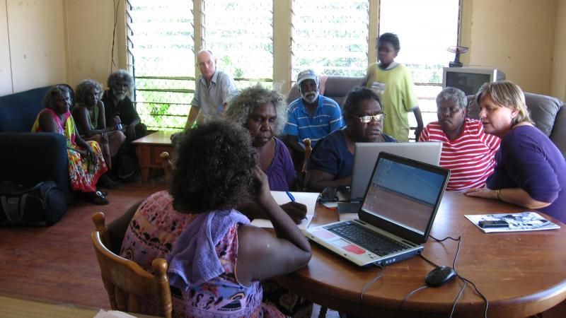 A group of people sitting around a table with laptops