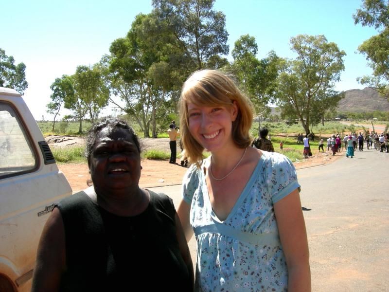 Two women are posing for a picture in front of a white van