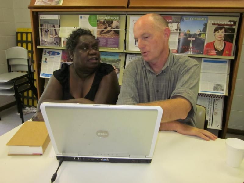 A man and a woman are looking at an hp laptop