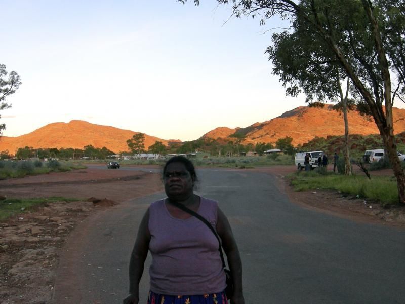 A woman standing on the side of a road with mountains in the background