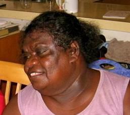 A woman is sitting in a chair with her eyes closed and smiling.