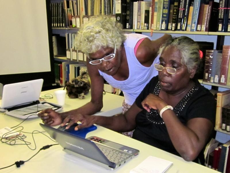 Two women are looking at a laptop in a library