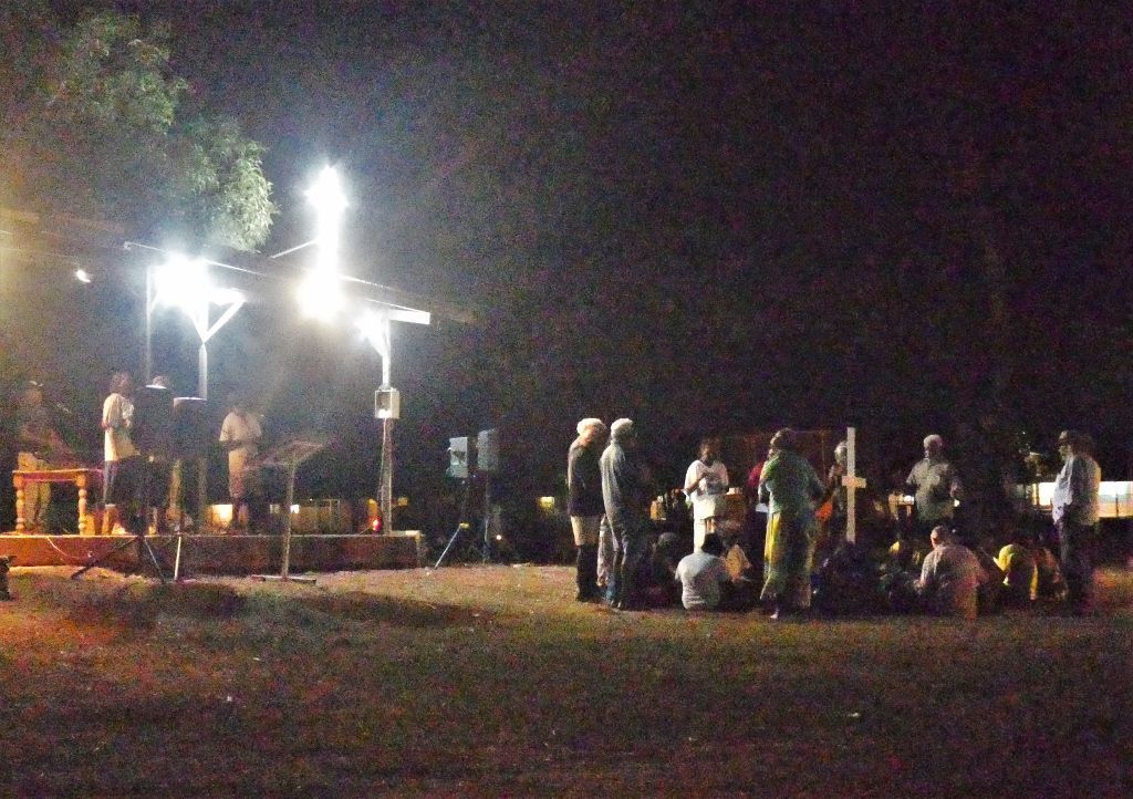 A group of people are gathered in a field at night