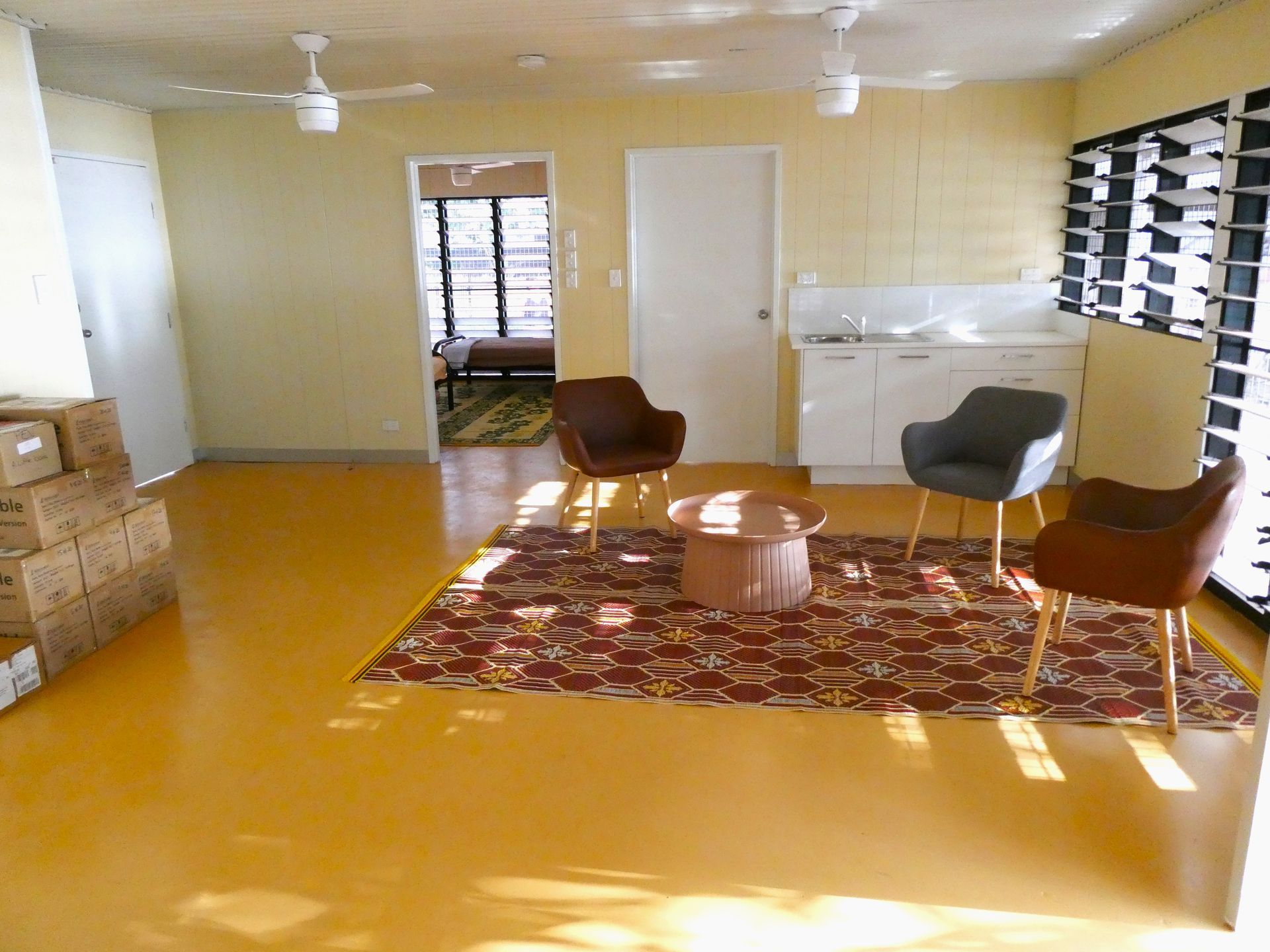 A living room with chairs and boxes on the floor