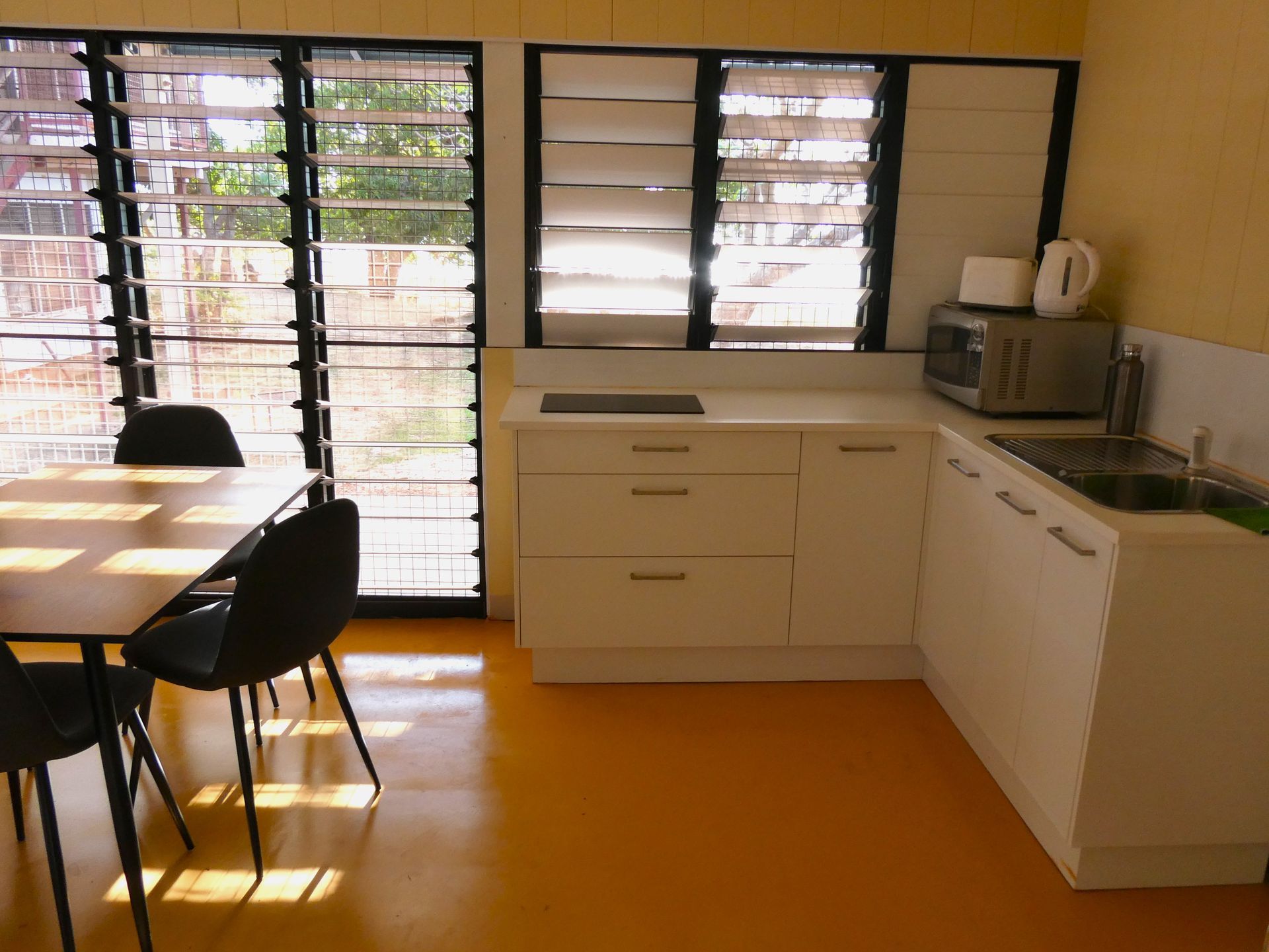 A kitchen with a table and chairs and a microwave
