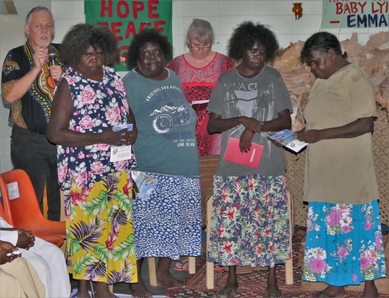 A group of women standing in front of a sign that says hope peace